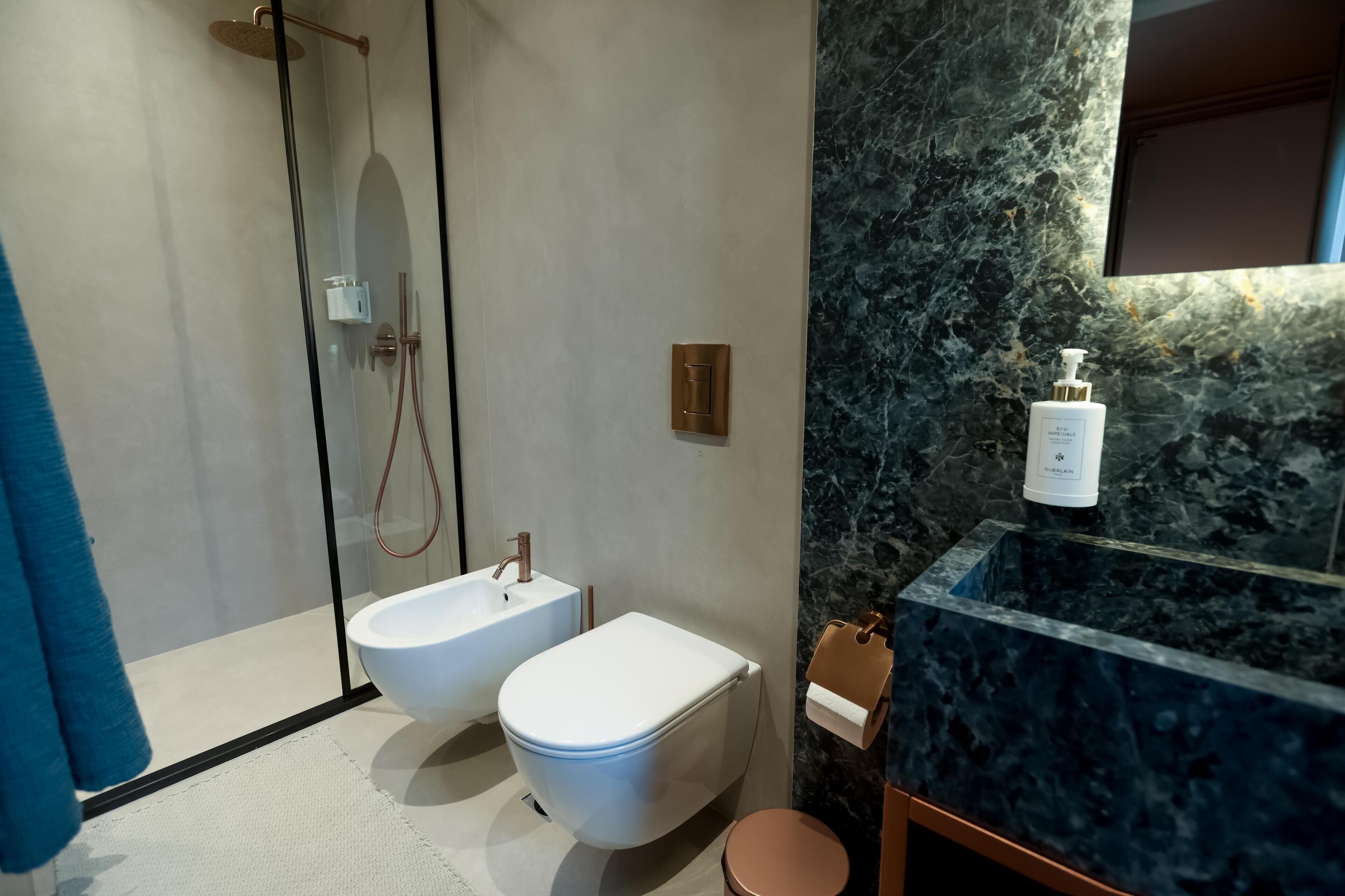 A modern bathroom with a glass-enclosed shower, a white sink, and a marble countertop.