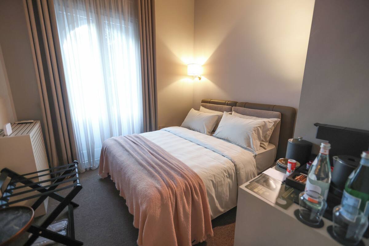 A hotel room with a bed, bedside table, and a chair.