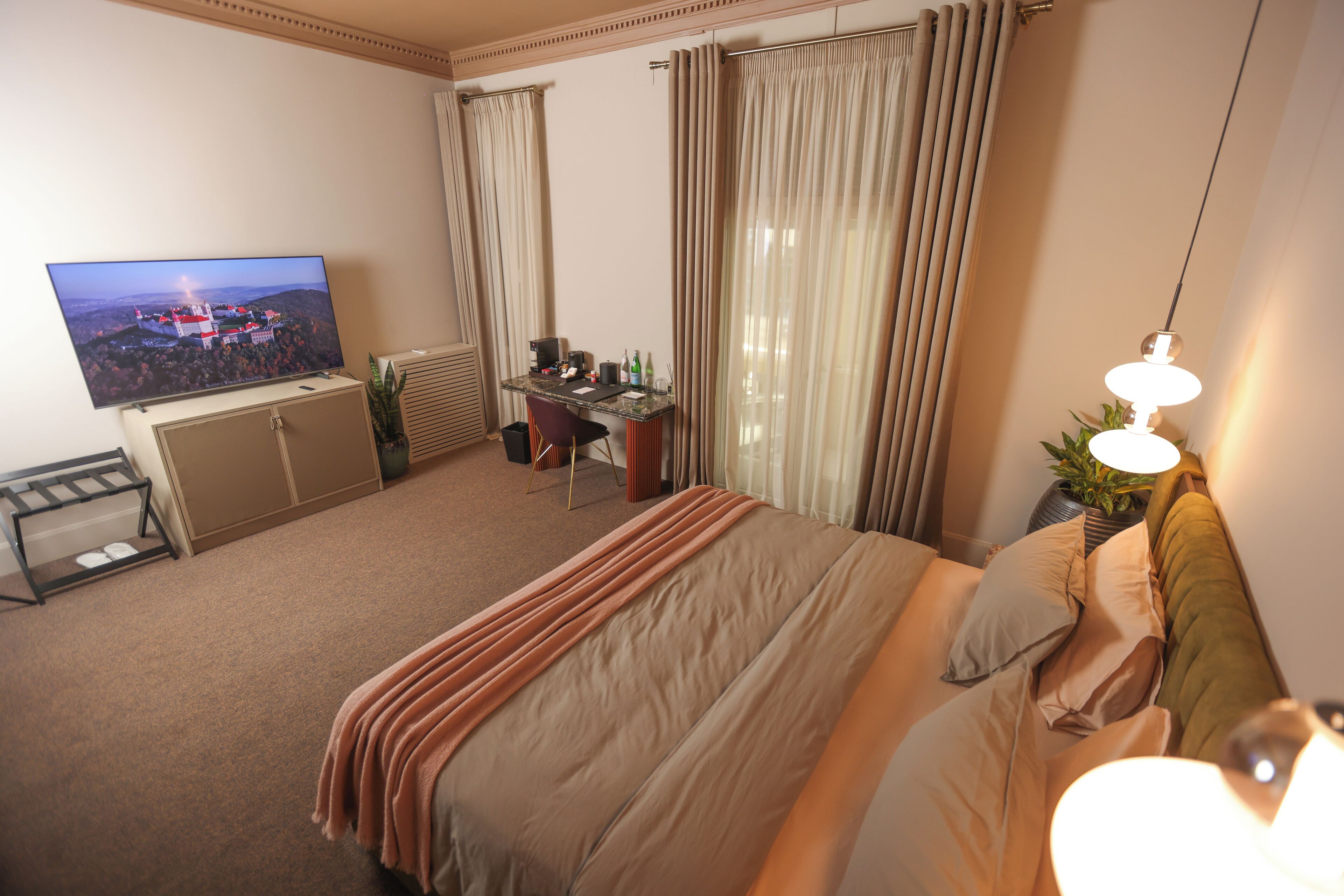 Una habitación de hotel con cama, escritorio, televisión y cortinas.