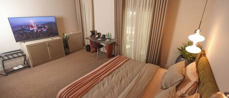 Una habitación de hotel con cama, escritorio, televisión y cortinas.
