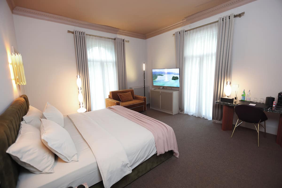 A hotel room with a bed, a TV, a desk, and a chair.