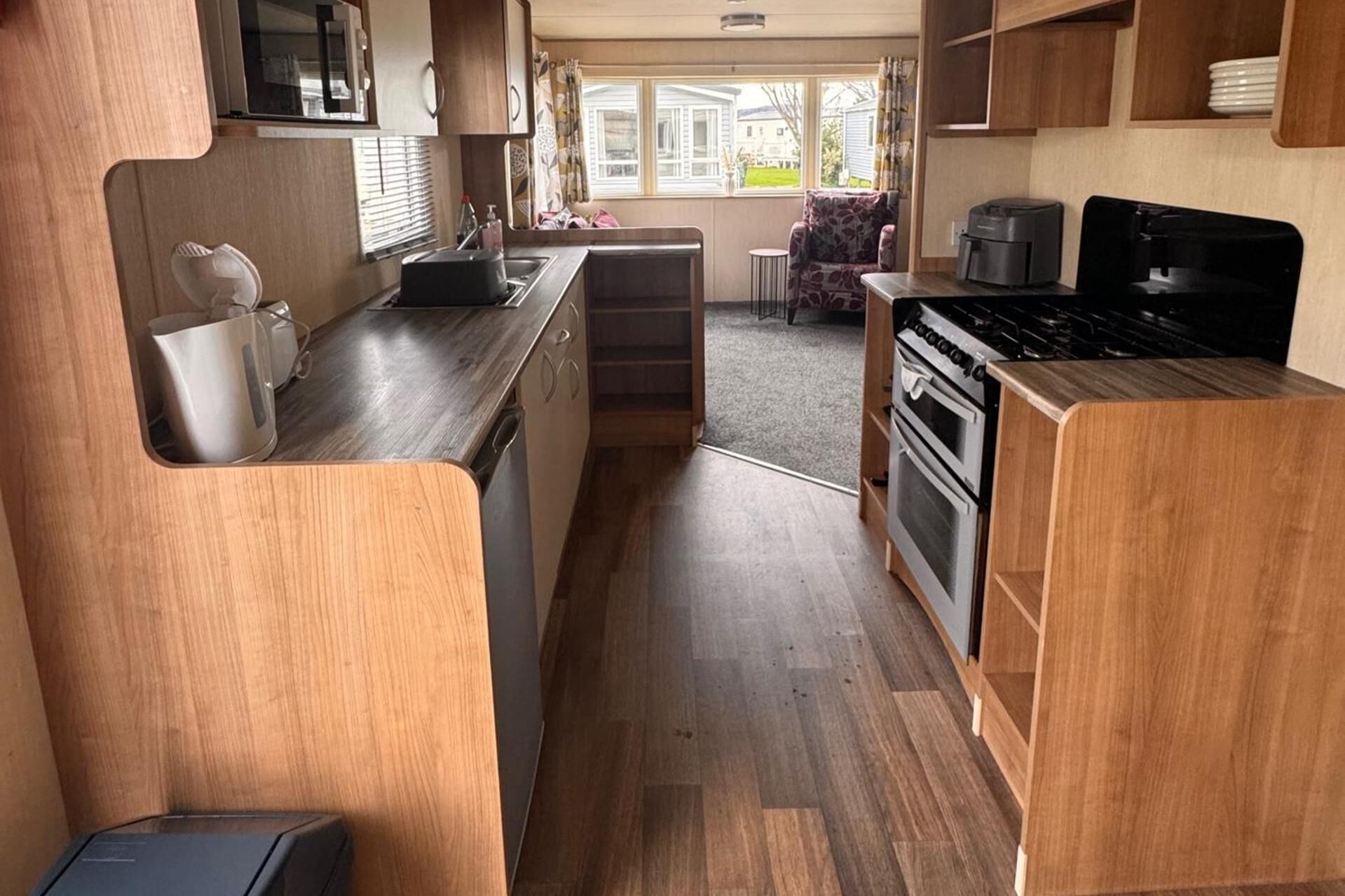 A compact kitchen with wooden cabinets, a stove, and a microwave.