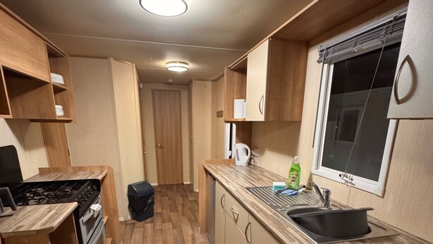 Una cucina compatta con mobili in legno, un fornello, un lavandino e una finestra.