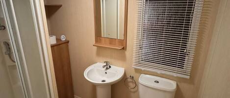 Un baño pequeño con lavamanos, inodoro y espejo sobre el lavamanos.