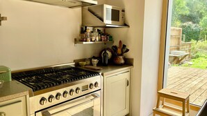 A compact kitchen with a gas stove, oven, microwave, and a small wooden table.