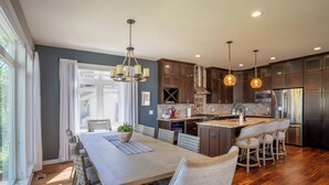 A modern kitchen with wooden cabinets, a central island, and pendant lighting.