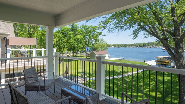 A covered outdoor area with wicker furniture and a view of a lake.