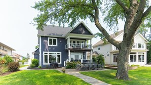 A two-story house with a balcony, a lawn, and a tree.