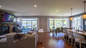 A spacious living room with a fireplace, a large sofa, and a dining area with bar stools.