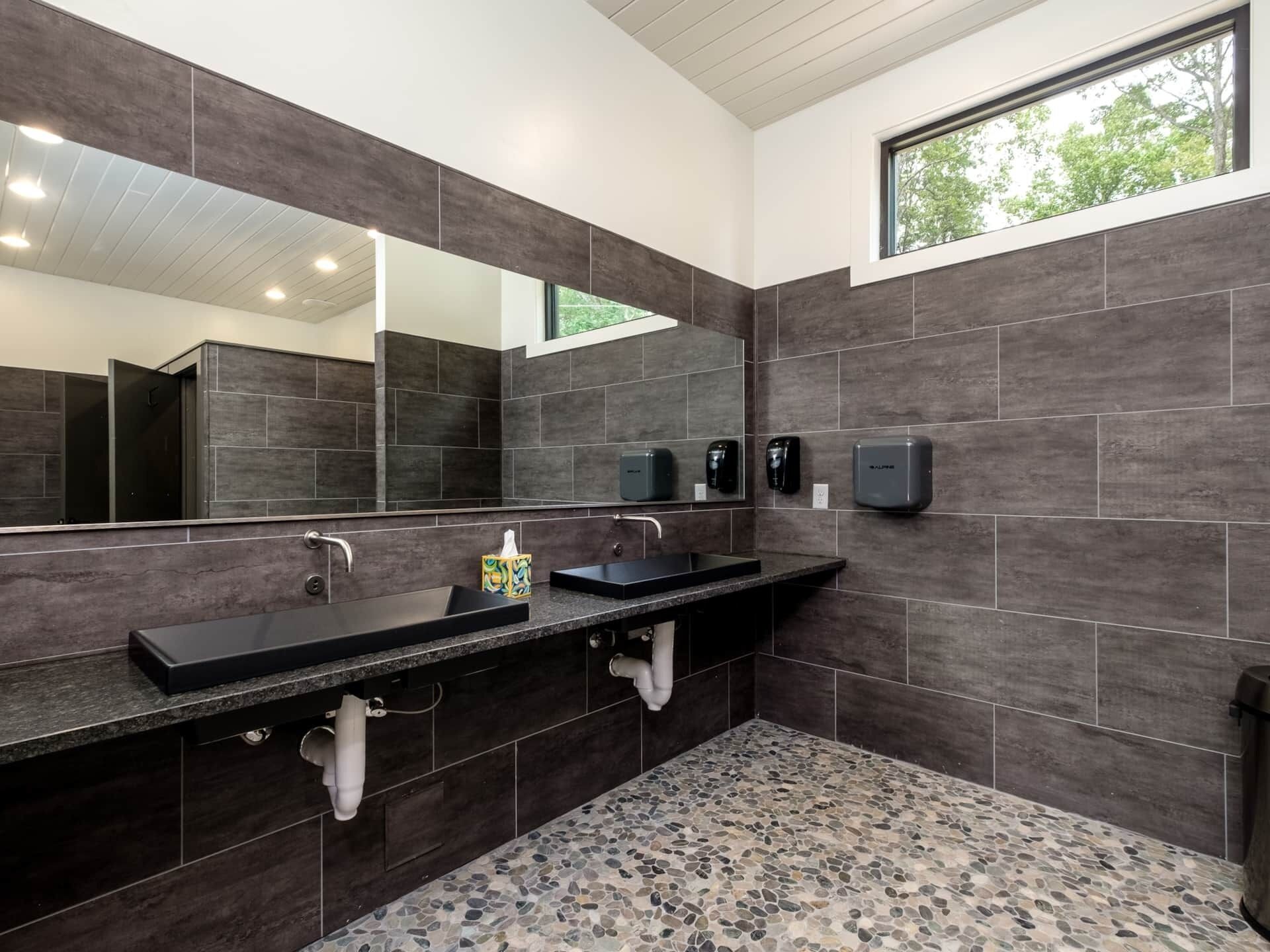 Une salle de bain moderne avec deux lavabos, un grand miroir et une fenêtre.