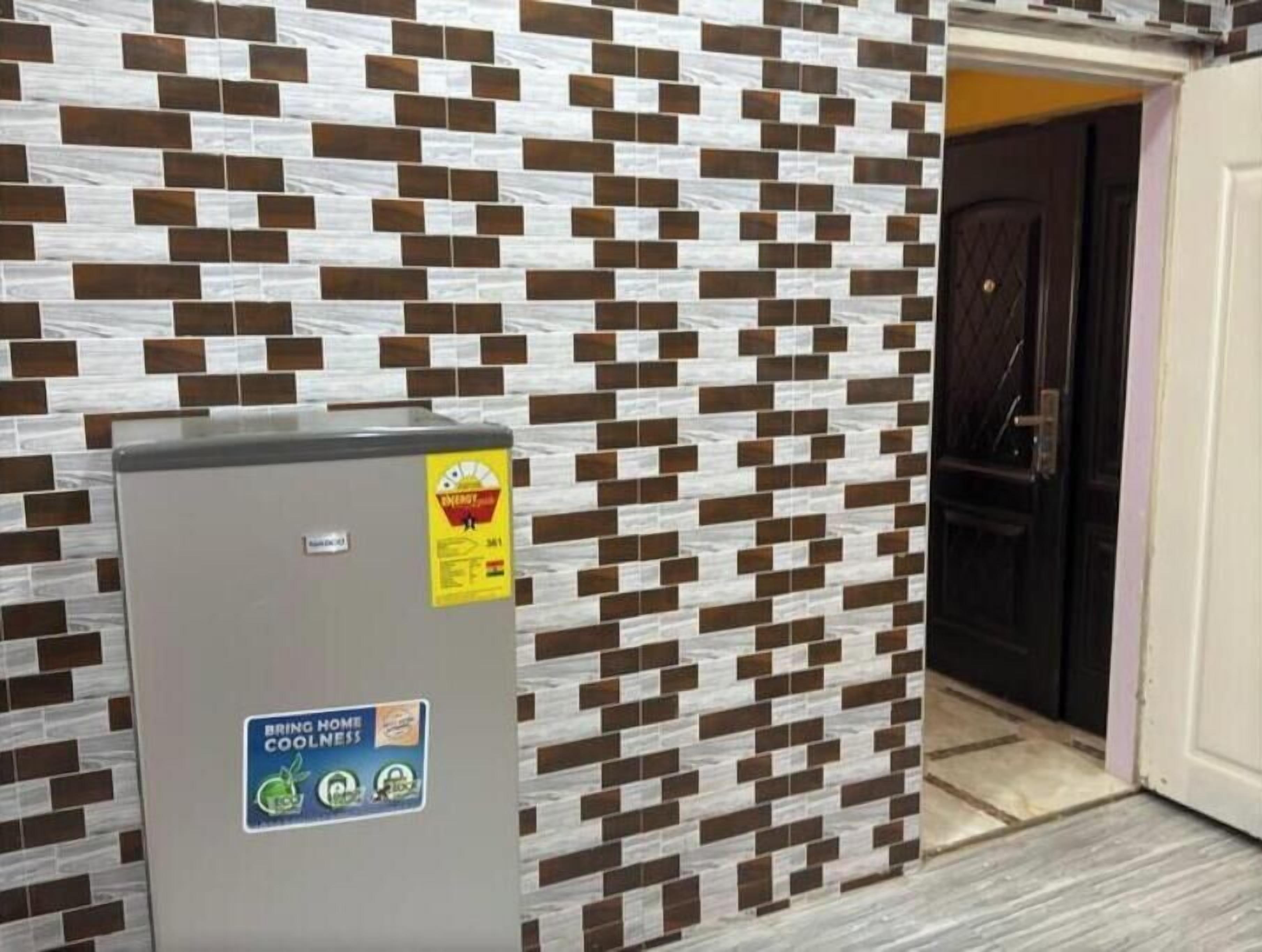 Un mur avec un motif en briques et une poubelle de recyclage ornée d’autocollants.