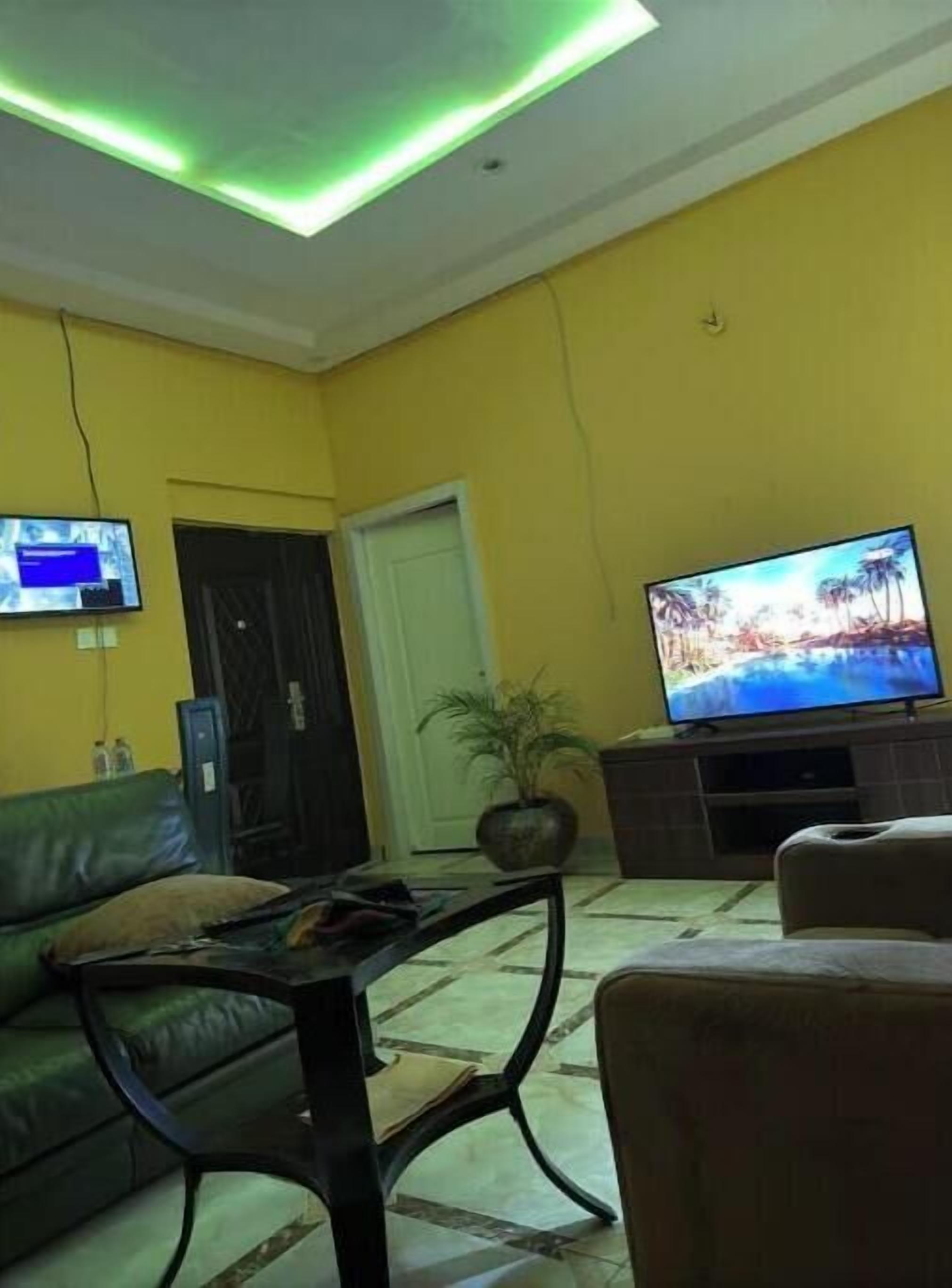 A living room with a yellow wall, a television, a sofa, and a coffee table.