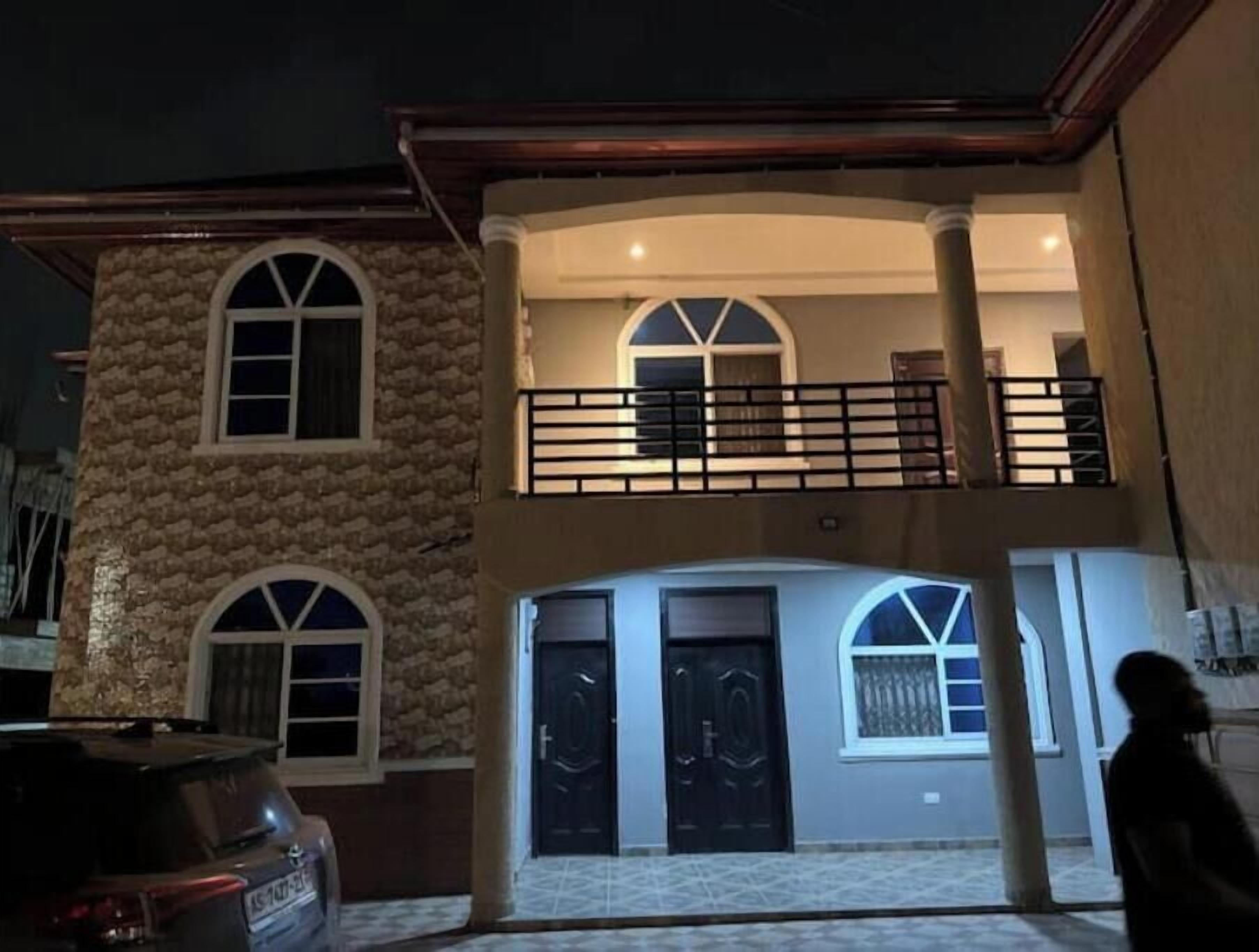 Un edificio a due piani con facciata in pietra, un balcone con ringhiera e due porte nere.