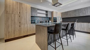 Una cocina moderna con armarios de madera, una isla central con taburetes altos y un horno empotrado.