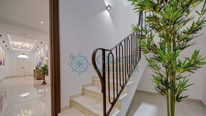 Una escalera con barandilla de metal, una planta en maceta y un piso pulido.