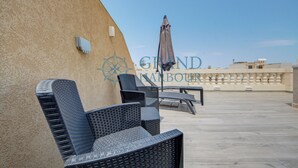 Terraza en la azotea con mobiliario de mimbre y una sombrilla grande.