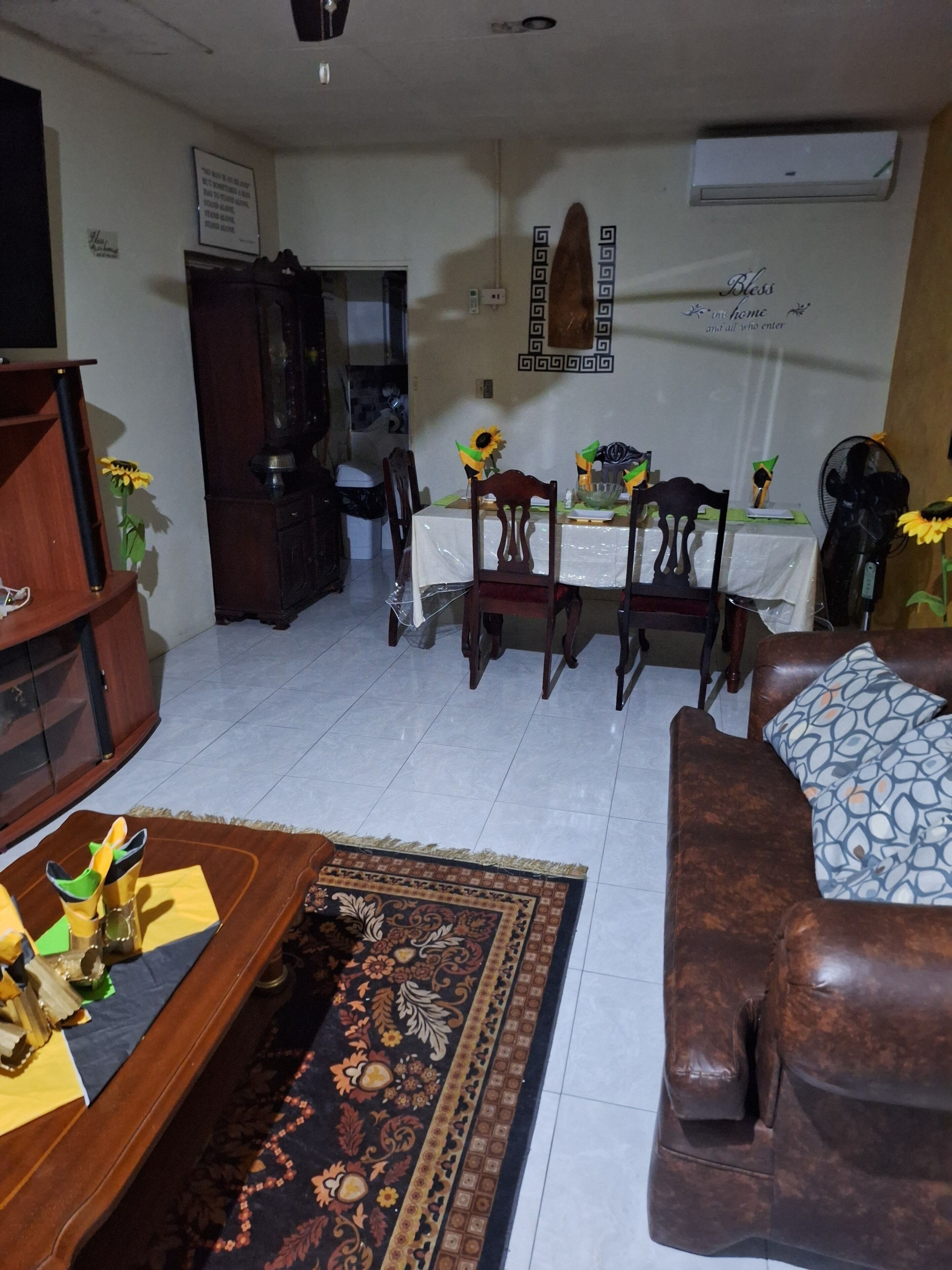 Ein Wohnzimmer mit einer Couch, einem Couchtisch und einem Esstisch mit Stühlen. An der Wand befinden sich ein Schrank und ein Spiegel.