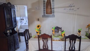 A dining area with a table set for four, surrounded by wooden chairs. A decorative wooden panel hangs on the wall above the table.