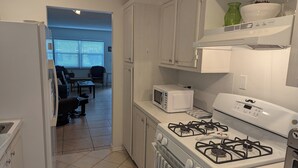 A kitchen with white cabinets, a gas stove, a microwave, and a refrigerator. - Amazing move in ready condo just 10 minutes from the beach. 65 plus community. (St Petersburg)