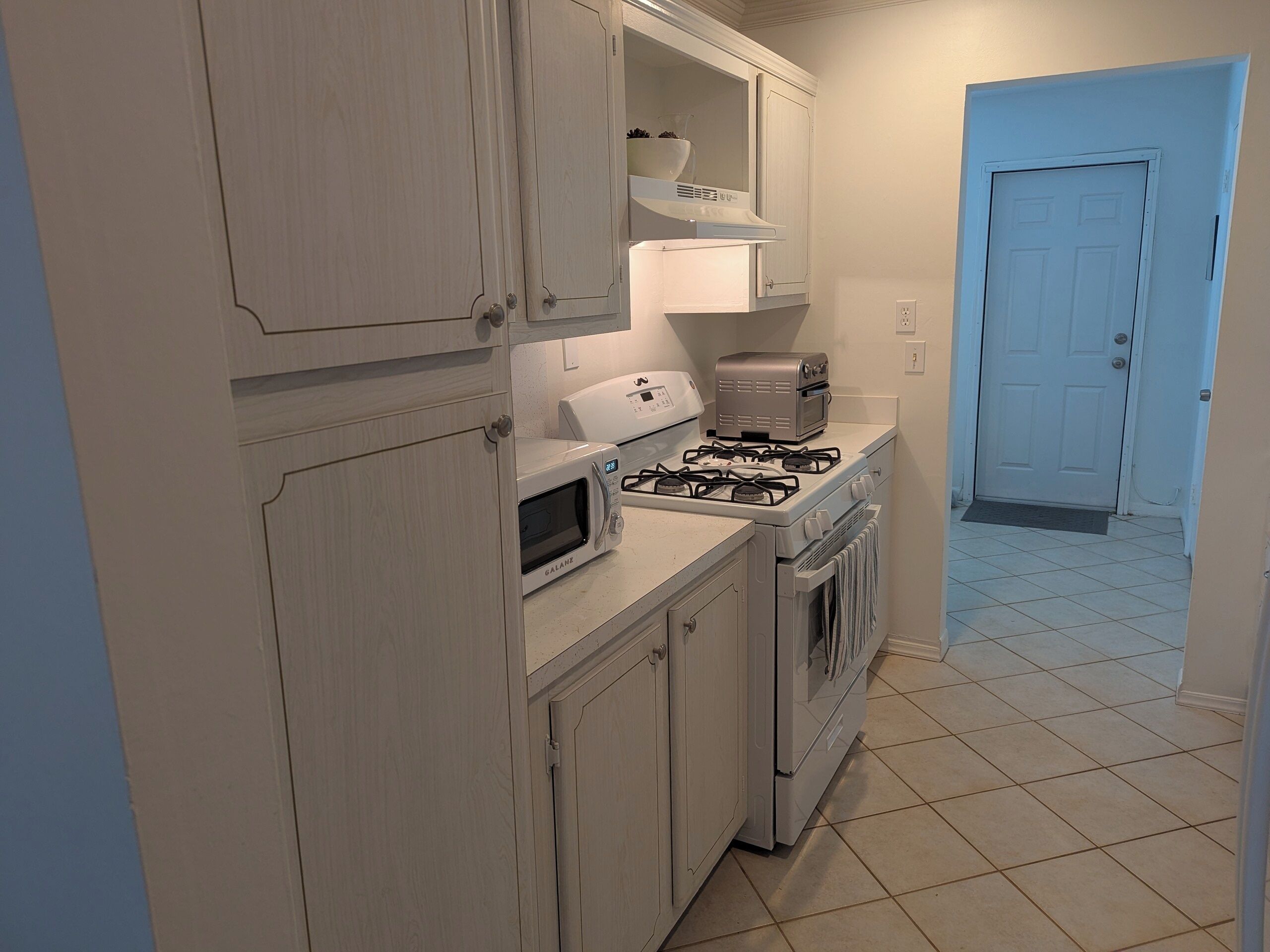 A kitchen with white cabinets, a microwave, a toaster, and a stove.