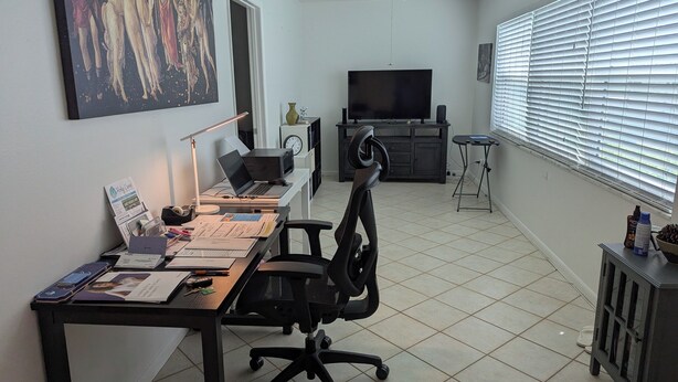 A home office with a desk, chair, laptop, and a television. - Amazing move in ready condo just 10 minutes from the beach. 65 plus community. (St Petersburg)