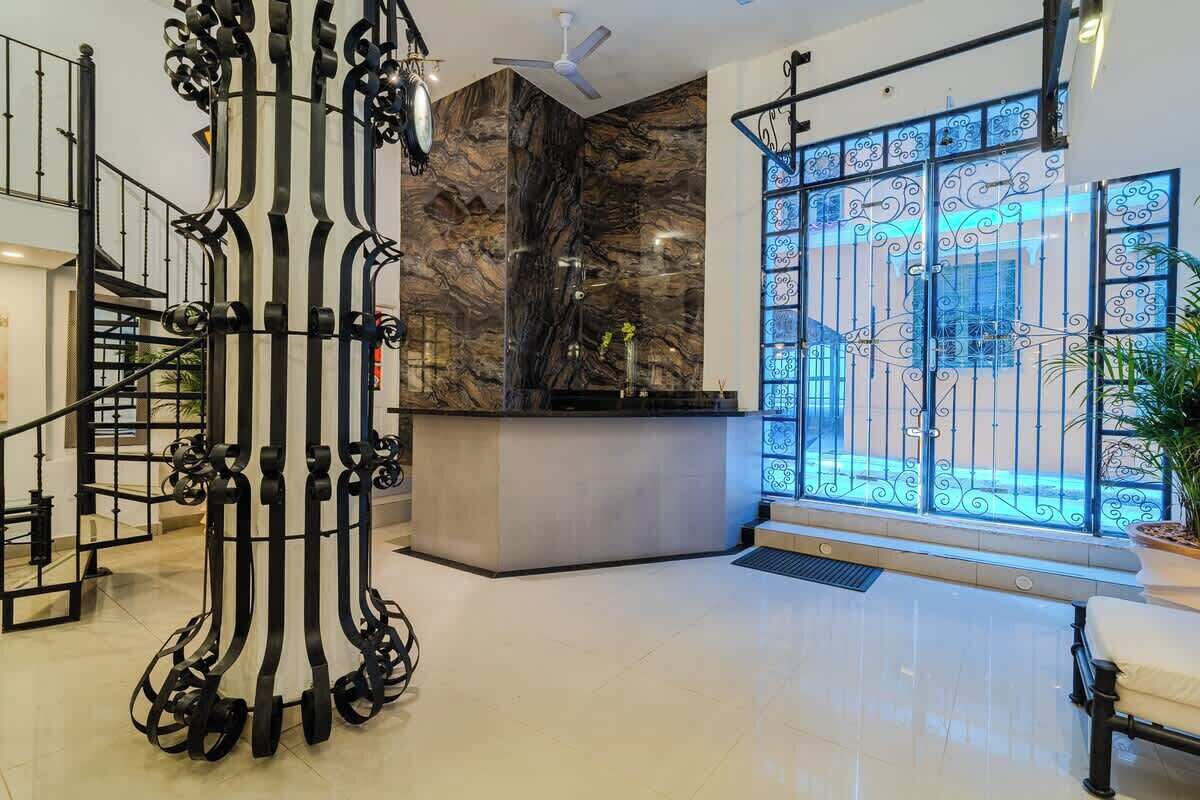 Eine moderne Lobby mit Marmorwand, einer Rezeption, einer Treppe mit schwarzen Geländern und einem großen Fenster mit schmiedeeisernen Gitterstäben.