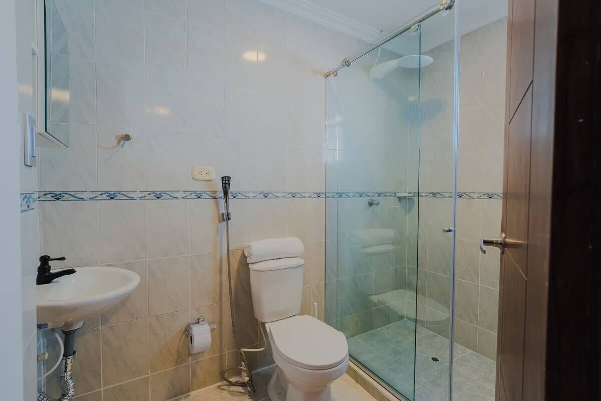 A bathroom with a glass shower enclosure, a toilet, and a sink.
