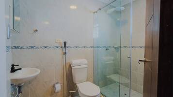 A bathroom with a glass shower enclosure, a toilet, and a sink.