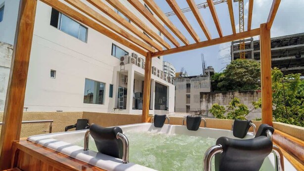 A rooftop hot tub with wooden railings and a view of surrounding buildings.