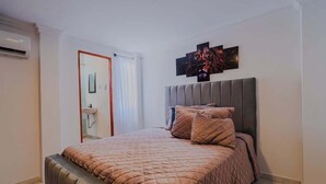 A bedroom with a bed, a headboard, and a wall-mounted artwork.