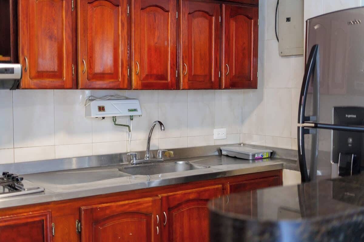 A kitchen with wooden cabinets, a stainless steel sink, and a refrigerator.
