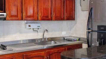 A kitchen with wooden cabinets, a stainless steel sink, and a refrigerator.