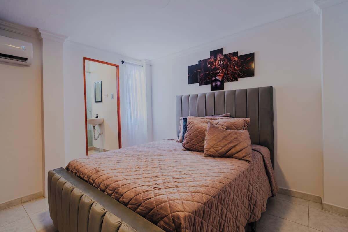 A bedroom with a large bed, a headboard, and a wall-mounted artwork.