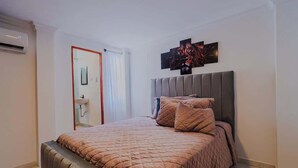 Un dormitorio con una cama grande, cabecera y una obra de arte colgada en la pared.