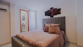 A bedroom with a large bed, a headboard, and a wall-mounted artwork.