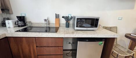 A compact kitchen with a built-in microwave, a coffee maker, and a dishwasher.