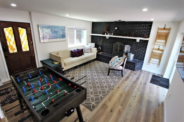 Ein Wohnzimmer mit Tischfußball, einer Couch, einem Kamin und einem gemusterten Teppich.