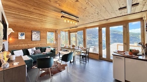 A spacious living area with a wooden ceiling, large windows, a dining table, and a kitchen area. - View mountain, terrace, parking, ski locker, 80m², Vars (Vars)