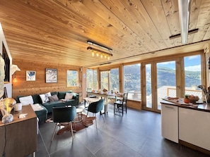 A spacious living area with a wooden ceiling, large windows, a dining table, and a kitchen area. - View mountain, terrace, parking, ski locker, 80m², Vars (Vars)