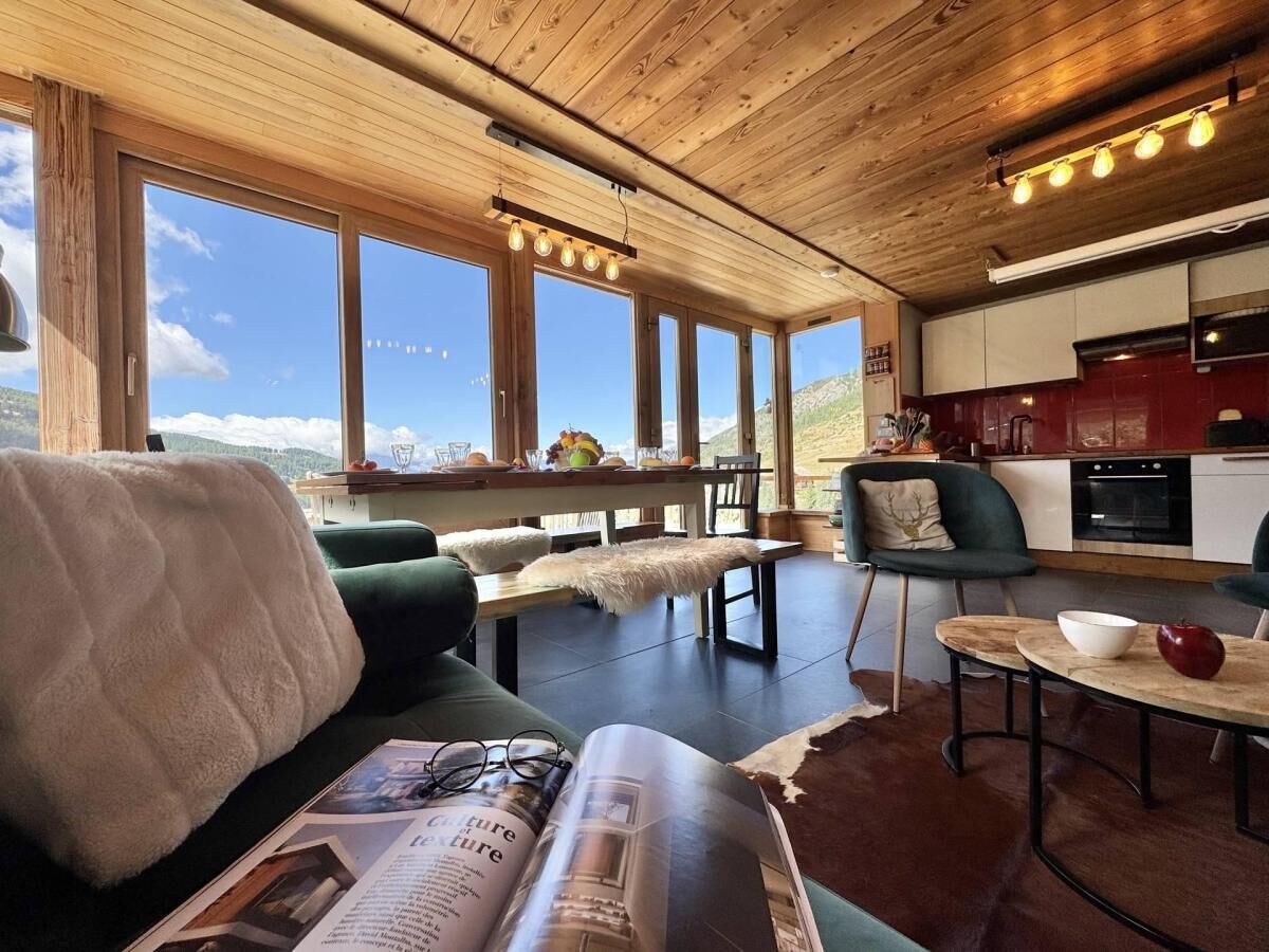 A cozy living area with a sofa, a dining table, and a kitchen in the background.