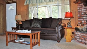A cozy living room with a leather sofa, a wooden coffee table, and a brick fireplace. - Southern Comfort Big Bear Lake (Big Bear Lake)