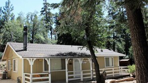A small, single-story building with a white porch and a chimney, surrounded by trees. - Southern Comfort Big Bear Lake (Big Bear Lake)