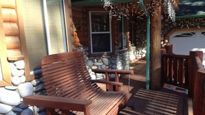 A wooden deck with a bench, stone wall, and a garage door. - DeCarlo House Big Bear Lake (Big Bear Lake)