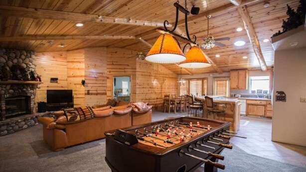A cozy room with a foosball table, a leather sofa, and a fireplace. - DeCarlo House Big Bear Lake (Big Bear Lake)