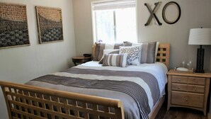 Un dormitorio con cama de madera, una mesita de noche, una lámpara y decoración en la pared.