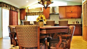 Un coin repas avec une table en bois, six chaises et un lustre.