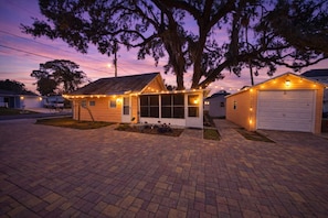 Une propriété r ésidentielle comprenant un garage, une petite maison avec un porche et un grand arbre.