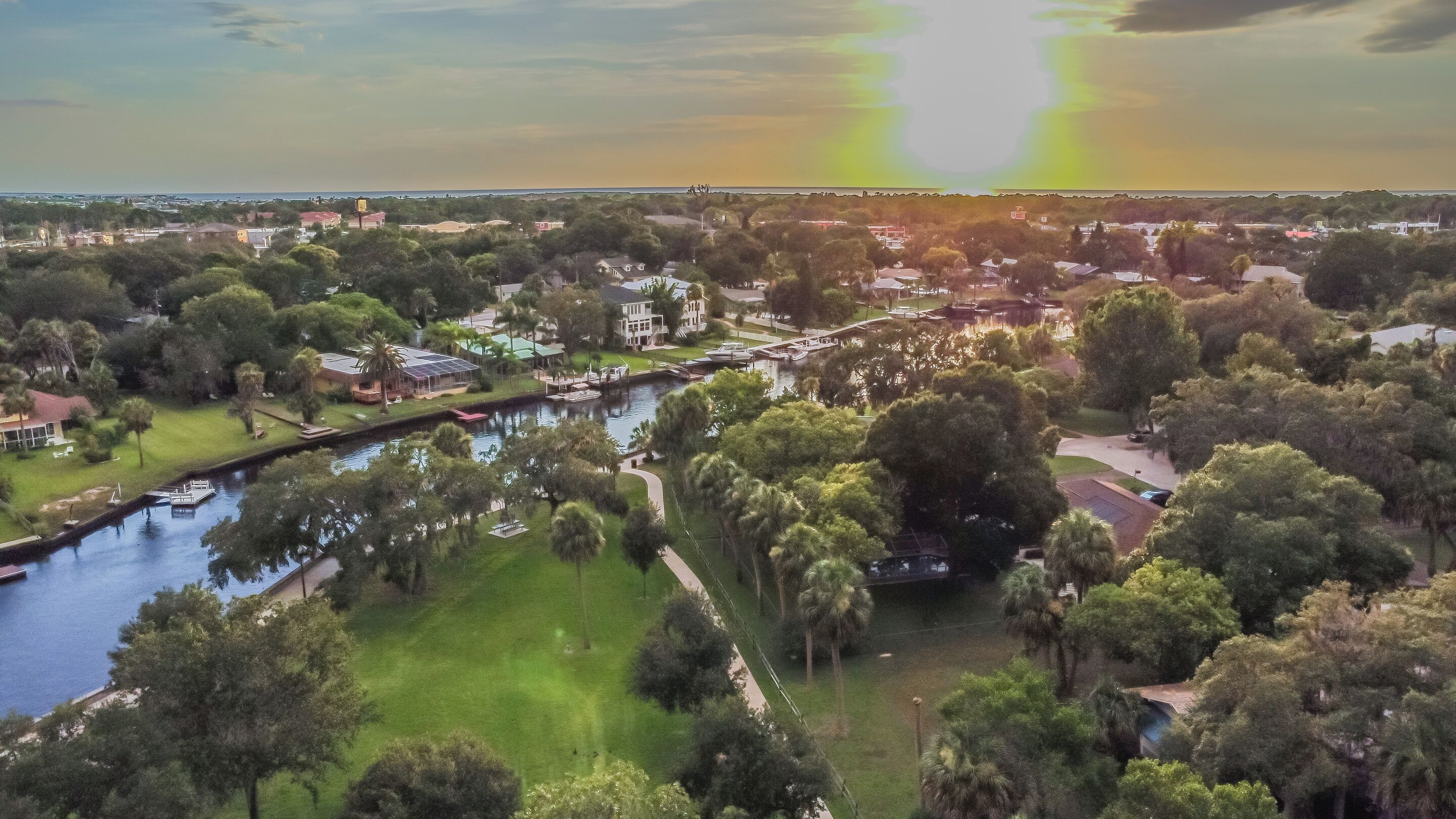 A riverside view of a residential area with houses, a marina, and a bridge.