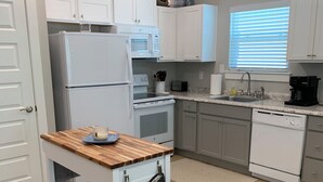 Una cocina moderna con armarios blancos, una encimera de madera, un horno empotrado y una cafetera.