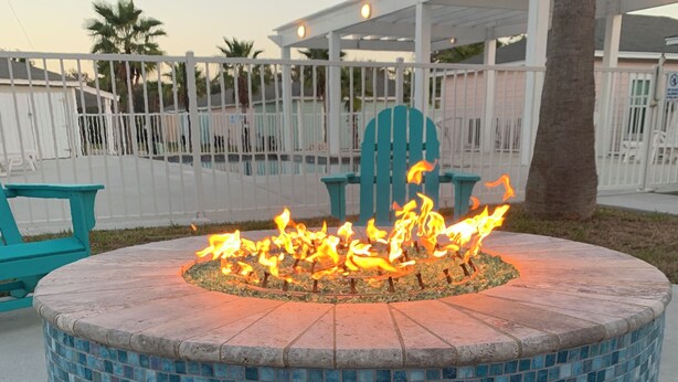 Una chimenea circular de mosaicos con estructura metálica, rodeada por una zona de concreto.